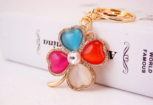 Close-up of four-leaf clover keychain with colorful cat eye stones and crystal inlay