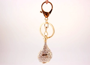 Detail view of the golden perfume bottle keychain encrusted with shiny white crystals