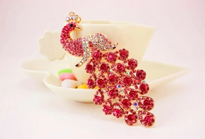 Detailansicht eines Pfau-Schlüsselanhängers mit rosa Kristallen an einer Kaffeetasse