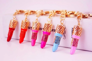 Close-up of sparkling rhinestone lipstick keychains in six vibrant colors with gold hardware