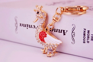 Macro side view of golden swan keychain with rhinestones resting on a white book