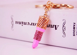 Macro shot of lipstick keychain with pink enamel and sparkling crystals on golden ring