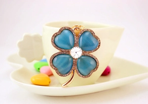 Detail of light blue opal four-leaf clover keychain with sparkling rhinestones in gold setting