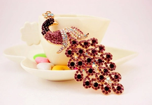 Detailaufnahme eines Pfauen-Schlüsselanhängers mit lila Strass und Roségold-Beschichtung