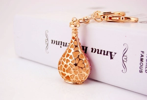 Macro shot of gold hollow heart keychain with pink rhinestones leaning on white book