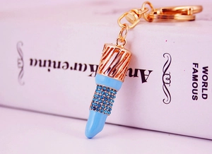 Macro shot of lipstick keychain with blue rhinestones and gold metal details