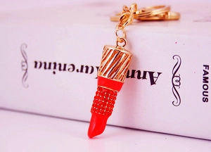 Macro view of rhinestone lipstick keychain with gold metal hollow design and red crystals