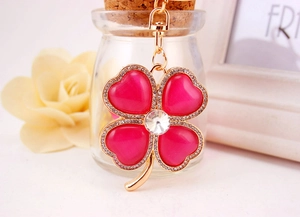 Close-up of pink heart-shaped opal clover keychain with gold metal and rhinestones