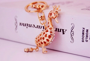 Detail of golden swan keychain featuring hollow floral design and crystal accents