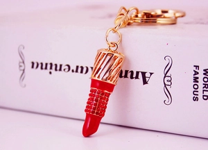 Detail of a sparkling rhinestone-studded lipstick keychain with gold metal finish