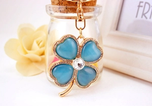 Detailed macro view of golden four-leaf clover keychain with blue cat-eye stones and crystals