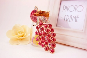 Nahaufnahme eines goldenen Pfauen-Schlüsselanhängers mit rosa Kristallen und Strass