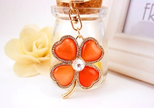 Detail of clover keychain with orange cat eye stones and sparkling crystals in gold finish