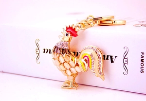 Détail d'un porte-clés coq doré avec corps en opale et accents de strass brillants