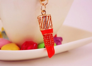 Détail d'un porte-clés rouge à lèvres scintillant avec strass rouges et métal doré