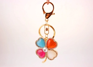 Detail of four-leaf clover keychain with cat-eye petals and rhinestones on gold ring