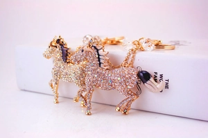 Macro shot of diamond-encrusted horse keychains with gold and silver plating details