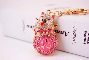 Detailed view of pink crystal pig keychain with gold-plated Fu character lucky charm
