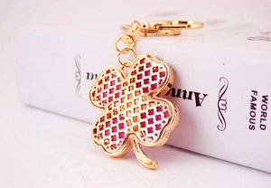 Macro shot of gold four-leaf clover keychain with red hollow pattern and lobster clasp