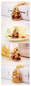 Detail of laughing Buddha keychain with red enamel and white crystals on golden metal