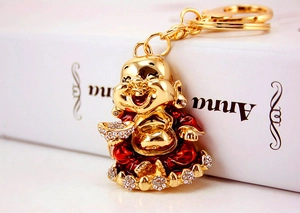 Detailed macro view of gold Buddha keychain with red enamel and sparkling crystal accents
