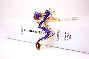 Detailed view of a golden dragon keychain encrusted with deep blue sparkling rhinestones