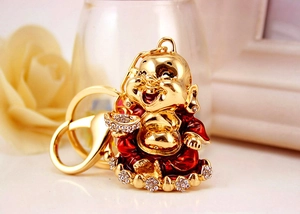 Close-up of golden Maitreya Buddha keychain with red enamel and sparkling crystal details
