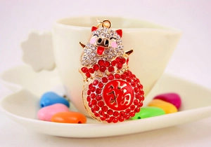 Close-up of a rhinestone pig keychain with a red lucky bag on a warm background