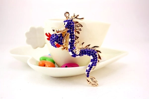 Detail of a golden dragon keychain encrusted with blue rhinestones on a coffee cup