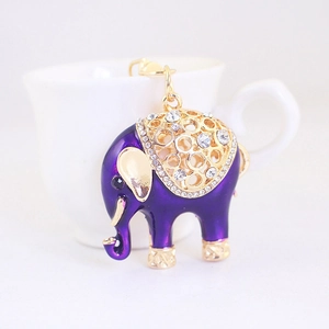 Simpatico portachiavi a elefante viola con strass posto sul bordo di una tazza bianca