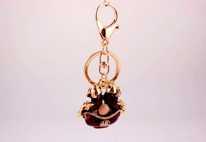 Close-up of golden carp keychain with red enamel, white bead and Fu character detail