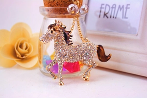 Detail of crystal horse keychain with golden finish and brown enamel hair and tail