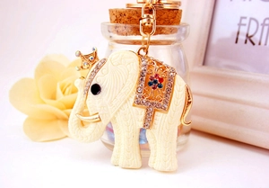 Close-up of elephant keychain with crystal crown and gold saddle on a floral background