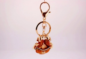 Detail of golden double carp koi keychain with red enamel and lucky Fu character charm