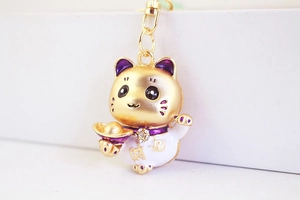 Détail du porte-clés chat porte-bonheur avec émail violet et accessoire de lingot d'or