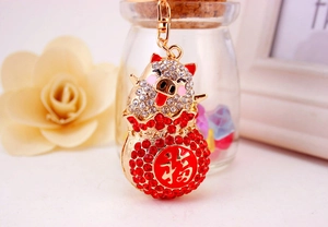 Detailed view of a golden pig keychain with sparkling diamonds and a red fortune bag charm