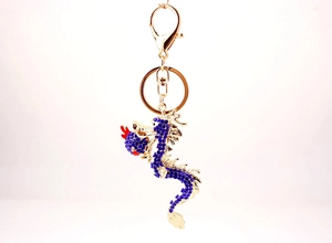 Detail of golden dragon keychain featuring blue crystals and ornate metalwork details
