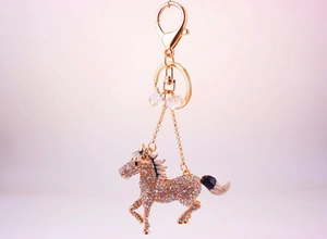 Macro shot of running horse keychain with sparkling rhinestones and golden hardware clasp