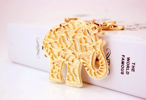 Macro detail of a golden hollow elephant keychain with crown and white resin filling