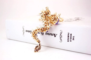 Detailed close-up of golden hollow dragon keychain with blue and red crystal rhinestones