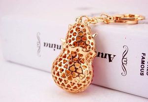 Detailed close-up of golden hollow peanut keychain with red rhinestones on a white book