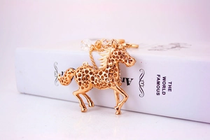 Detailed view of a golden horse keychain with hollow metalwork and crystal bead accents
