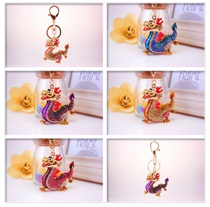 Close-up of four colorful crystal dragon keychains with shiny metal hooks and rings