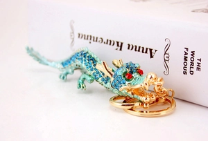 Gros plan d'un porte-clés dragon avec strass bleus et anneau doré près d'un livre