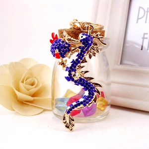 Exquisite golden dragon keychain with blue rhinestones hanging on a glass vase