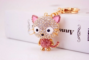 Close-up of golden alloy cartoon cat keychain with white and pink crystal rhinestones