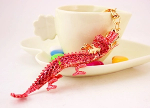 Détails d'un porte-clés dragon rose rouge avec strass brillants et mousqueton en métal doré