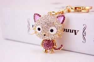 Macro detail of cartoon cat keychain with purple crystals and gold plated metal