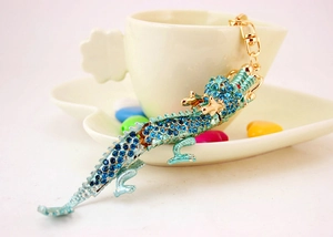 Détail de porte-clés dragon avec strass bleus accroché sur le bord d'une tasse blanche