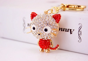 Close-up of golden cat keychain with sparkling white and red rhinestones on a white book